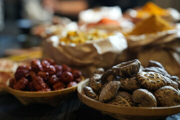 Colorful selection of dried herbs, spices, and natural ingredients in paper bags on rustic market...