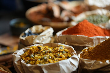 Colorful selection of dried herbs, spices, and natural ingredients in paper bags on rustic market...
