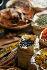 Close-up of traditional Asian dried herbs and ingredients in bamboo baskets, including shiitake mushrooms, jujube dates, and citrus slices. Organic natural food concept with soft background blur.