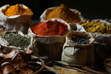 Colorful selection of dried herbs, spices, and natural ingredients in paper bags on rustic market...