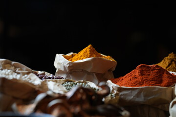 Colorful selection of dried herbs, spices, and natural ingredients in paper bags on rustic market...