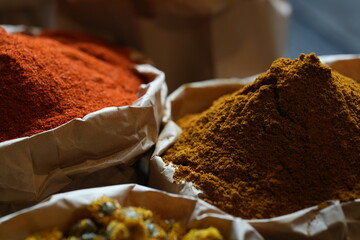 Colorful selection of dried herbs, spices, and natural ingredients in paper bags on rustic market...