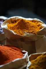 Colorful selection of dried herbs, spices, and natural ingredients in paper bags on rustic market table. Traditional Asian and herbal medicine concept.