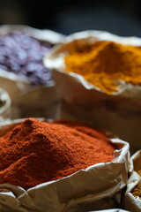 Colorful selection of dried herbs, spices, and natural ingredients in paper bags on rustic market table. Traditional Asian and herbal medicine concept.