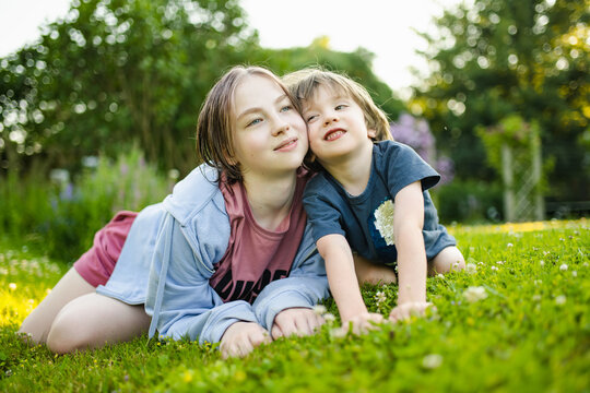 Cute big sister cuddling with her toddler brother. Adorable teenager girl hugging her small sibling. Children exploring nature.