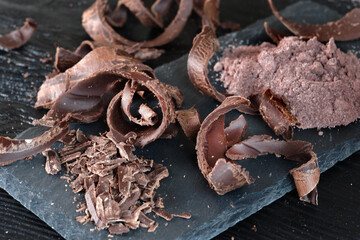 Pieces of dark chocolate on a black wooden background. Close-up