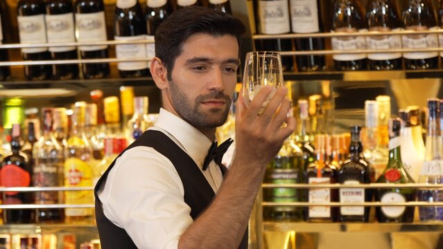 Good looking bartender chilling glass with ice for serving customer at beverage bar counter of welcome drink with charm professionalism, making great first impression warm smiling greeting. Vinosity.