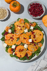 Winter salad. Fresh persimmon and pomegranate spinach salad with feta and pine nuts
