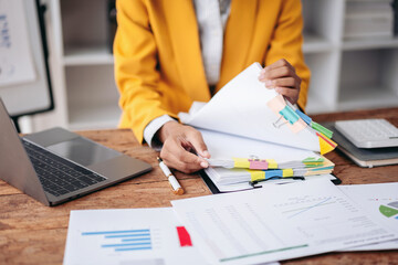 Adult Woman Hands Organizing Financial Documents at Office Desk with Laptop Charts and Calculator for Business Report Analysis