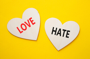 Love vs Hate symbol. Concept word Love vs Hate on wooden hearts. Beautiful yellow background....