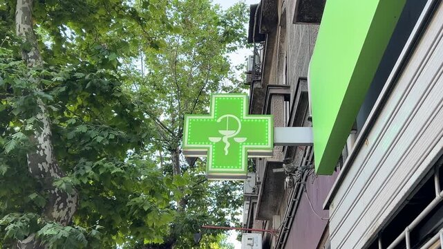 Pharmacy outdoor sign. Green illuminated cross sign blinking.