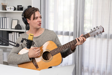 Host channel in smart singer with smiling face, playing guitar along singing, broadcasting on...