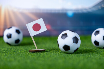 Miniature Japanese flag with soccer balls on a green field, representing national sports pride and...