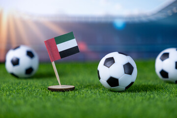 United Arab Emirates flag and soccer balls on green grass, representing national team pride in global football competition