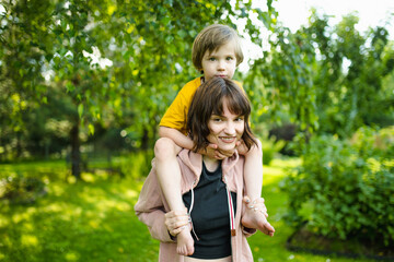 Fototapeta premium Cute big sister cuddling with her toddler brother. Adorable teenager girl hugging her small sibling. Children exploring nature.