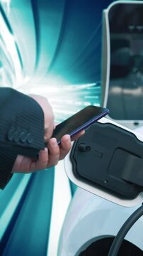 Progressive man check electric car's battery status with smartphone at charging station with technology background of binary code flying through votex. EV car concept with modern technology.