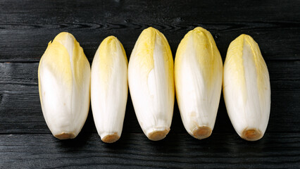 Raw chicory or endives salad roots on wooden background