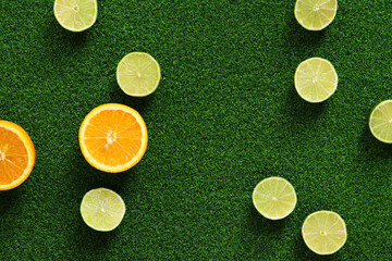 Orange and lime halves on grass background, top view. Summer background. Oranges and limes on...