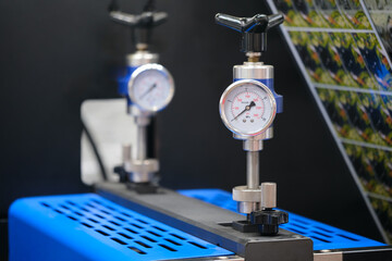 Two pressure gauges are attached to an industrial printing machine on polyethylene film, gauges are probably used to measure pressure in a pneumatic or hydraulic conveyor system.
