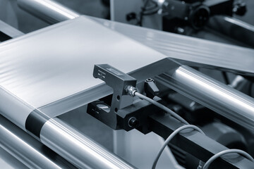 A roll of plastic polyethylene film is cut by a food packaging machine. Industrial concept background.