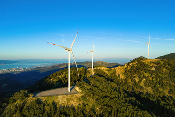 Wind turbines in the wind energy farm in mountain with city on background. Aerial view. Energy...