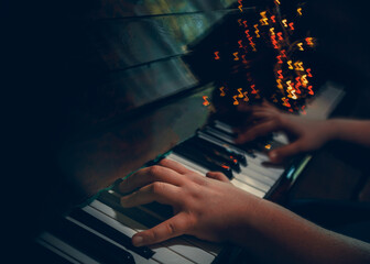 The piano player hands, playing music abstract photography with notes shaped bokeh. Dark music style background