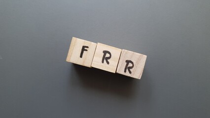 FRR acronym made of wooden letter cubes on dark background. Fonds de Réserve pour les Retraites...