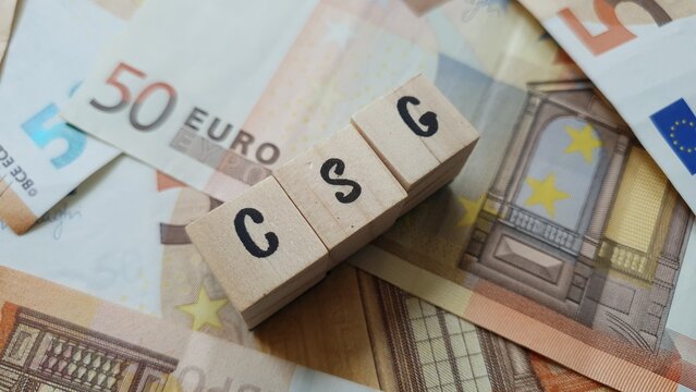 CSG acronym made of wooden letter cubes on pile of Euro banknotes. Contribution Sociale G&eacute;n&eacute;ralis&eacute;e (General Social Contribution, a tax funding social security)