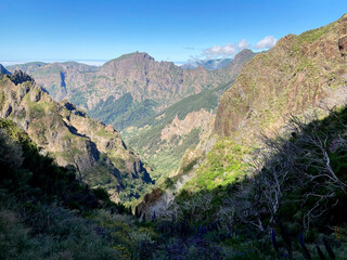 Stunning view of mountains with lush greenery and dramatic cliffs under a clear blue sky in a vibrant landscape