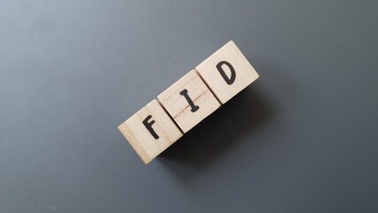 FID acronym made of wooden letter cubes on dark background. Fonds d’Investissement de Proximité...