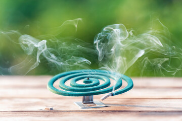 Smoldering mosquito coil in summer garden on wooden table, insect protection
