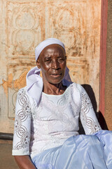 village single zezuru old african woman wearing a headscarf sited in front of the house , in the yard, close portrait