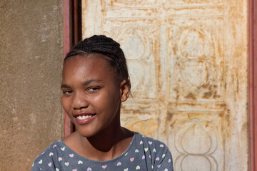 village single young african teenager with braids standing in front of the house , in the yard, close portrait