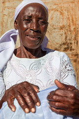 village single zezuru old african woman wearing a headscarf sited in front of the house , in the yard, close portrait