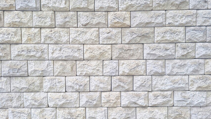 Textured stone wall with rectangular light grey beige blocks arranged in horizontal rows. Natural rough surface pattern for architecture and construction concept. Mockup stage template