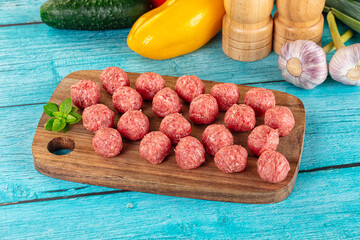 Raw beef meatballs over board