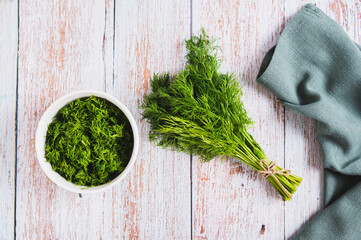 Bunch of fresh dill and chopped dill in a bowl on a table top view