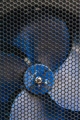 Background, texture of propeller from electric fan behind metal mesh.