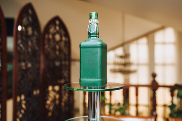Beautiful decorated green bottle with design with alcohol stands on a stand in honor of the wedding...