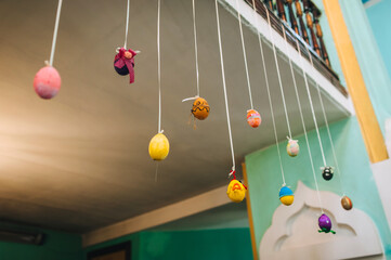 Colorful, decorated eggs hanging on ropes indoors. Photography, Easter concept.