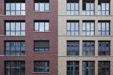 Front view of a residential building featuring contrasting red and beige brick sections. The facade...