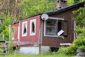 Derelict wooden house with broken windows and rusty satellite dish