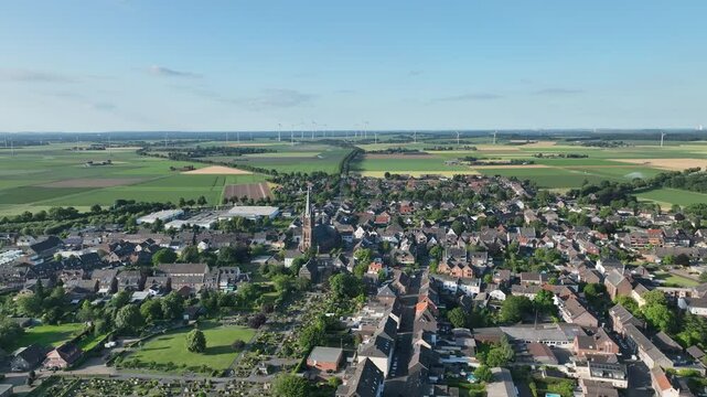 Luftbildaufnahme von Aldekerk bei Kerken mit Bahnhof an einem sonnigen Sommerabend. Weitwinkel-Drohnenflug &uuml;ber D&auml;cher, Felder und Gleisanlagen im warmen Licht der Abendsonne.