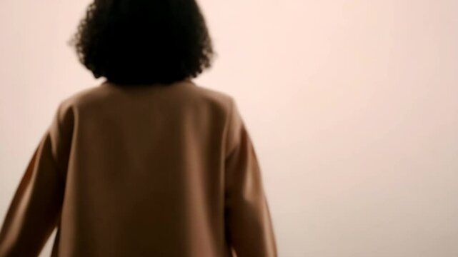 minimalistic scene featuring person in pastel pink sweater standing against ultrabright light gray background