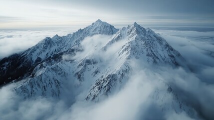 Obraz premium Snow-covered mountains peek through a layer of clouds, creating a breathtaking landscape that captures the beauty and majesty of nature in a serene atmosphere.