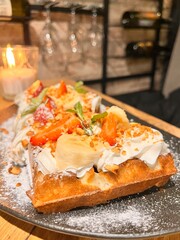 Belgian waffles with a scoop of ice cream, fruits and berries on a blurred background of wine bottles and glasses. Food background