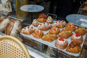 Danish pastry on a a cafe showcase behind the window: view from the street. Tasty buns and croissants in a bakery in Copenhagen, Denmark