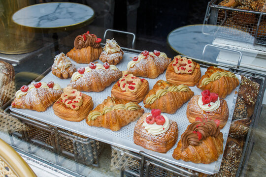 Danish pastry on a a cafe showcase behind the window: view from the street. Tasty buns and croissants in a bakery in Copenhagen, Denmark.