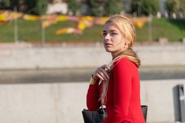 Fototapeta premium Elegant woman in red dress stands confidently on city street during daytime