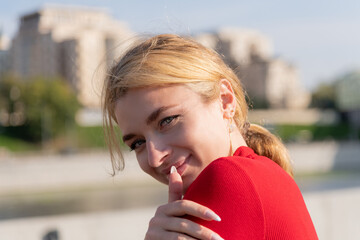 Woman in red dress poses confidently on city street during sunny day